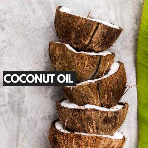 Coconut Oil Against Piled Coconuts